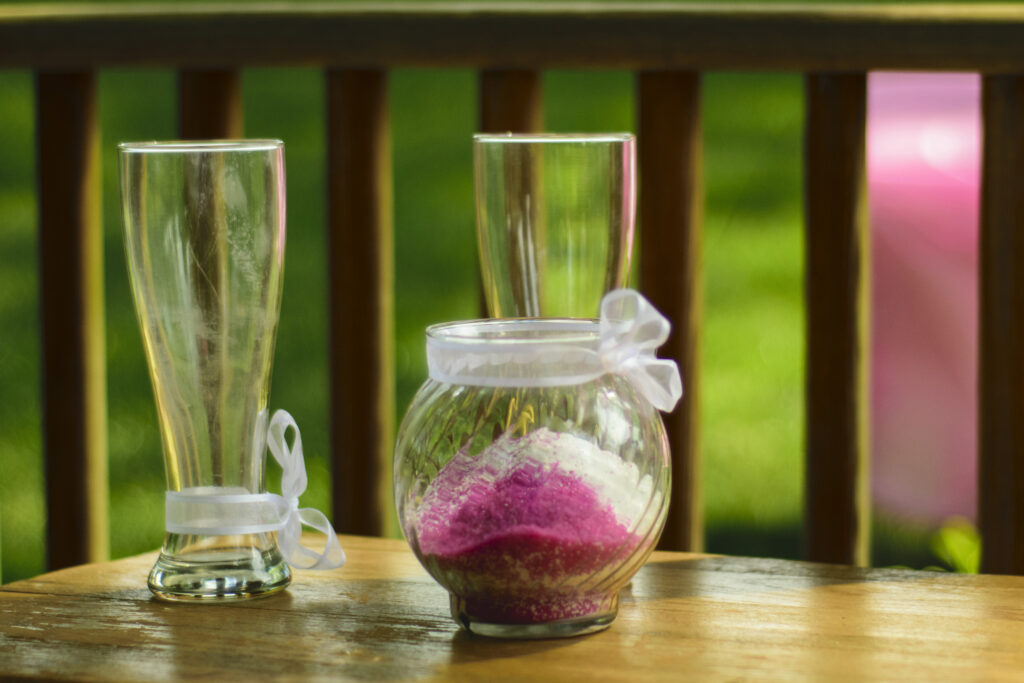 An image of mixed colors of sand and two glasses.